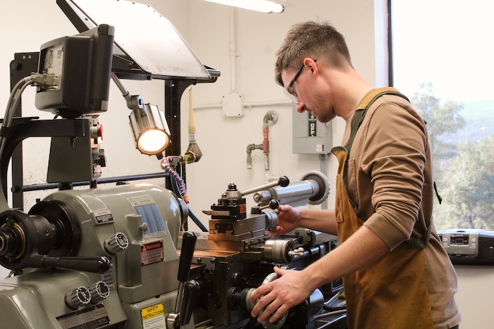 man at machine engineering a part